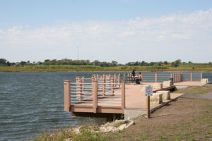 pedestrian dock over park lake with people at picnic table