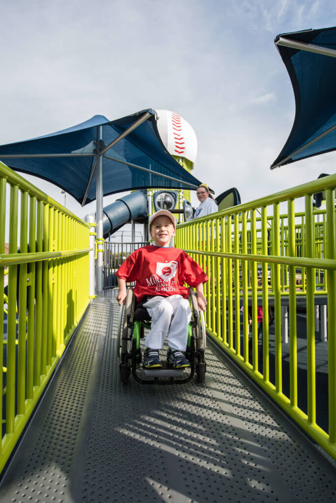 young boy in wheelchair playing on playground