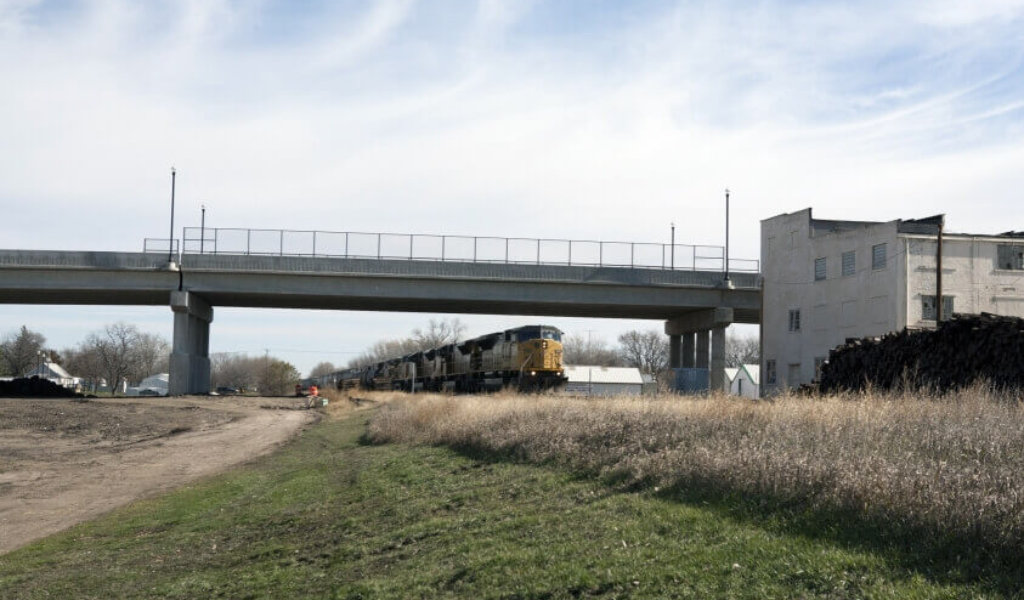 Train running on tracks underneath a highway overpass in Jefferson Iowa.