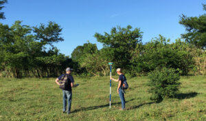 Civil engineers taking survey data in the middle of a grassy field in Colombia