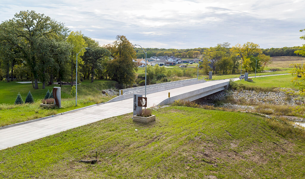 A custom aluminum handrail along the south side of the new bridge and decorative monuments provide the finishing touch on the new bridge over a realigned segment of Sugar Creek.