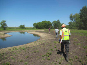 man in reflective vest conducts site walk along stream