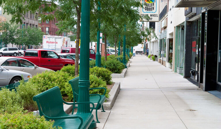 The downtown Clinton, Iowa streetscape uses planting beds, decorative lighting, and seating to create an inviting public space for pedestrians.