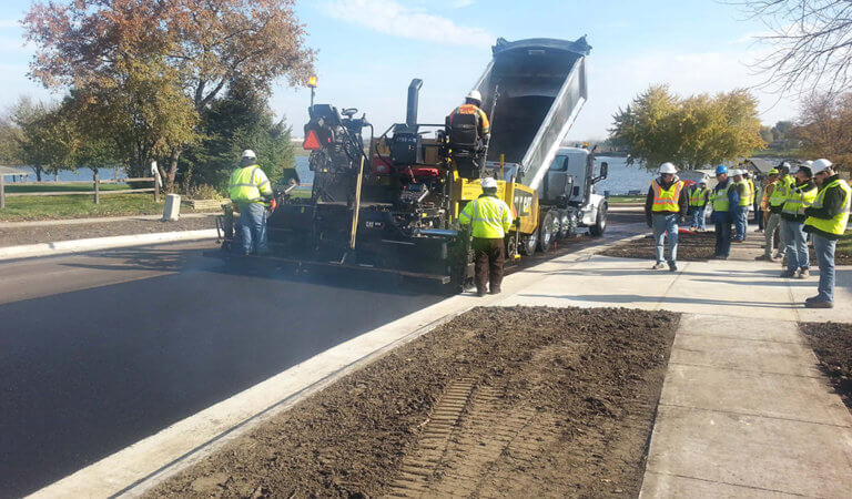 Hot mix asphalt being installed on residential street. Numerous crew and contractors on sight.