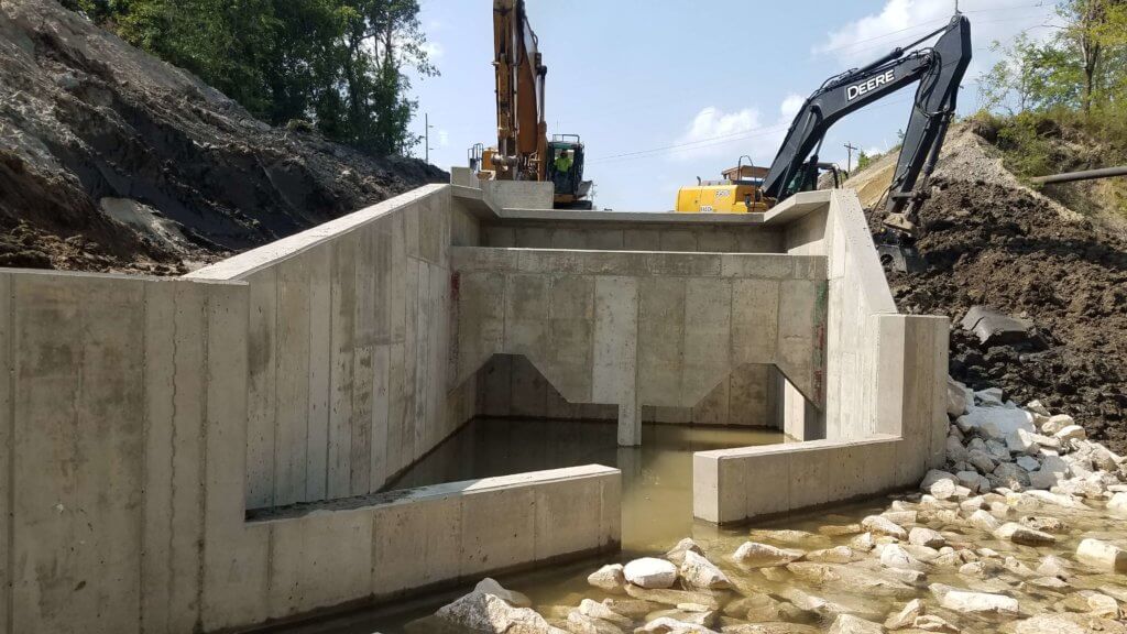 large concrete stormwater outlet structure with construction machinery behind it