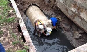 three men working on a sewer pipe.
