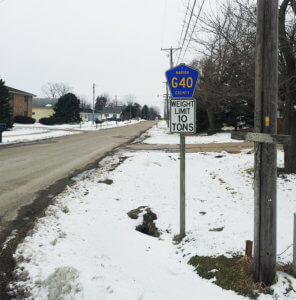 snowy roadway with weight limit sign along the curb
