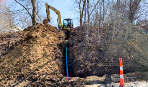 Large machine digging trench for blue water pipe.