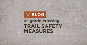 Tan gravel background with title at grade crossing Trail safety measures blog