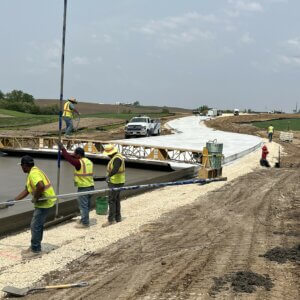 Work crew pouring concrete for a roadway