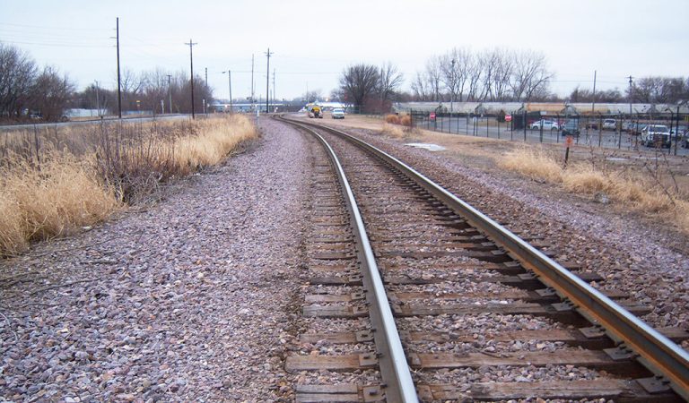 ||Railroad tracks with industrial building behind|