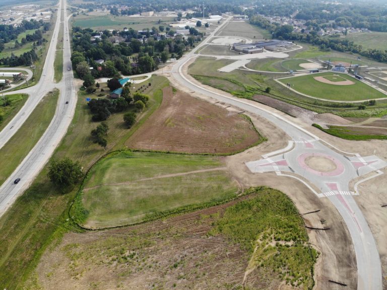 Roundabout in Anamosa Iowa|Roundabout in Anamosa Iowa|Overview of US 151 Grade Separation and Roundabout in Anamosa Iowa|Roundabout design showcasing lighting and signage in Anamosa Iowa|Man cutting the ribbon for US 151 Grade Separation and Roundabout in Anamosa Iowa||US 151 Grade Separation and Roundabout: Anamosa