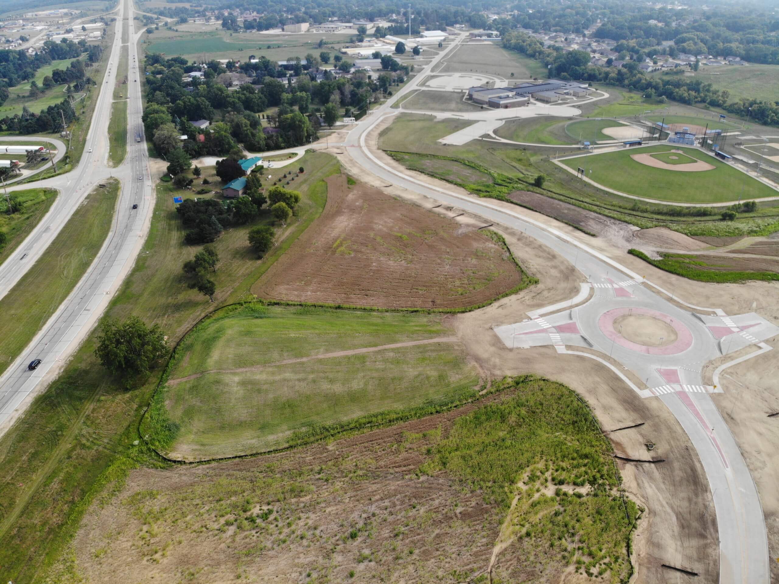 Roundabout in Anamosa Iowa|Roundabout in Anamosa Iowa|Overview of US 151 Grade Separation and Roundabout in Anamosa Iowa|Roundabout design showcasing lighting and signage in Anamosa Iowa|Man cutting the ribbon for US 151 Grade Separation and Roundabout in Anamosa Iowa||US 151 Grade Separation and Roundabout: Anamosa