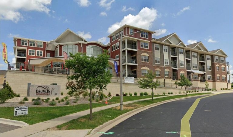 Large brick apartment building on a hill|brick multi-use building on a corner|view of community center buildings from down the street