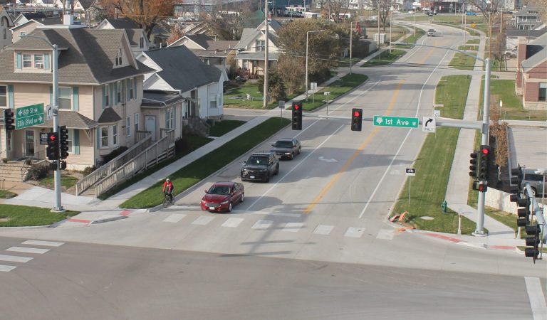 Overlaid pavement on 1st Ave with railroad crossing in the background|Aerial view of Ellis Boulevard and 6th street NW Connector & 1st ave rehabilitation in Cedar Rapids Iowa|Aerial view of Ellis Boulevard and 6th street NW Connector & 1st ave rehabilitation in Cedar Rapids Iowa|Aerial view of Ellis Boulevard and 6th street NW Connector & 1st ave rehabilitation in Cedar Rapids Iowa|Railroad crossing|Roundabouts Streamline Traffic Flow|Cars driving around the roundabout creating efficient traffic flow|1st Ave & 6th Street Intersection facing North Before & After Construction
