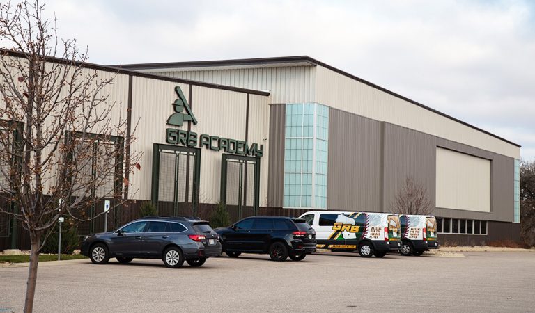 Front entrance of recently completed pre-engineered metal building.|Recently completed Trowbridge Group Fle Building parking lot.|Trowbridge Group Flex Building building directly south of the GRB Academy.|Bioretention basic assist GRB academy with stormwater runoff.|GRB academy company vans parked near entrance.