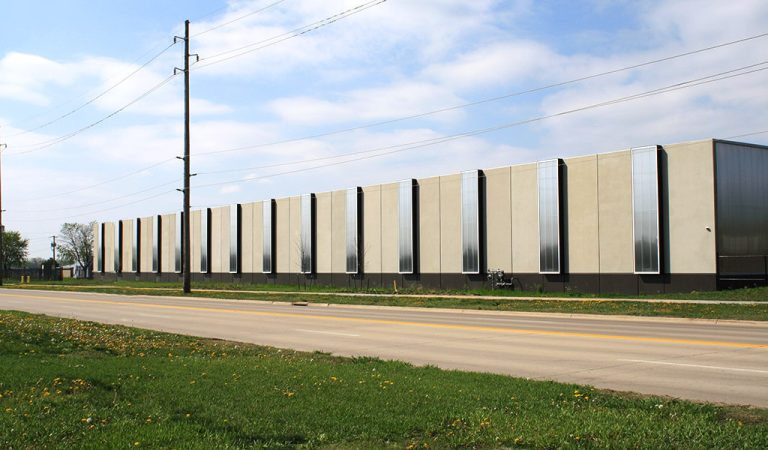 concrete and glass design for iowa public works facility|firetruck next to fire training tower|public works vehicles lined up inside warehouse|Loading docks on the back of the iowa public works facility building||black and white rendering highlighting project area in color.