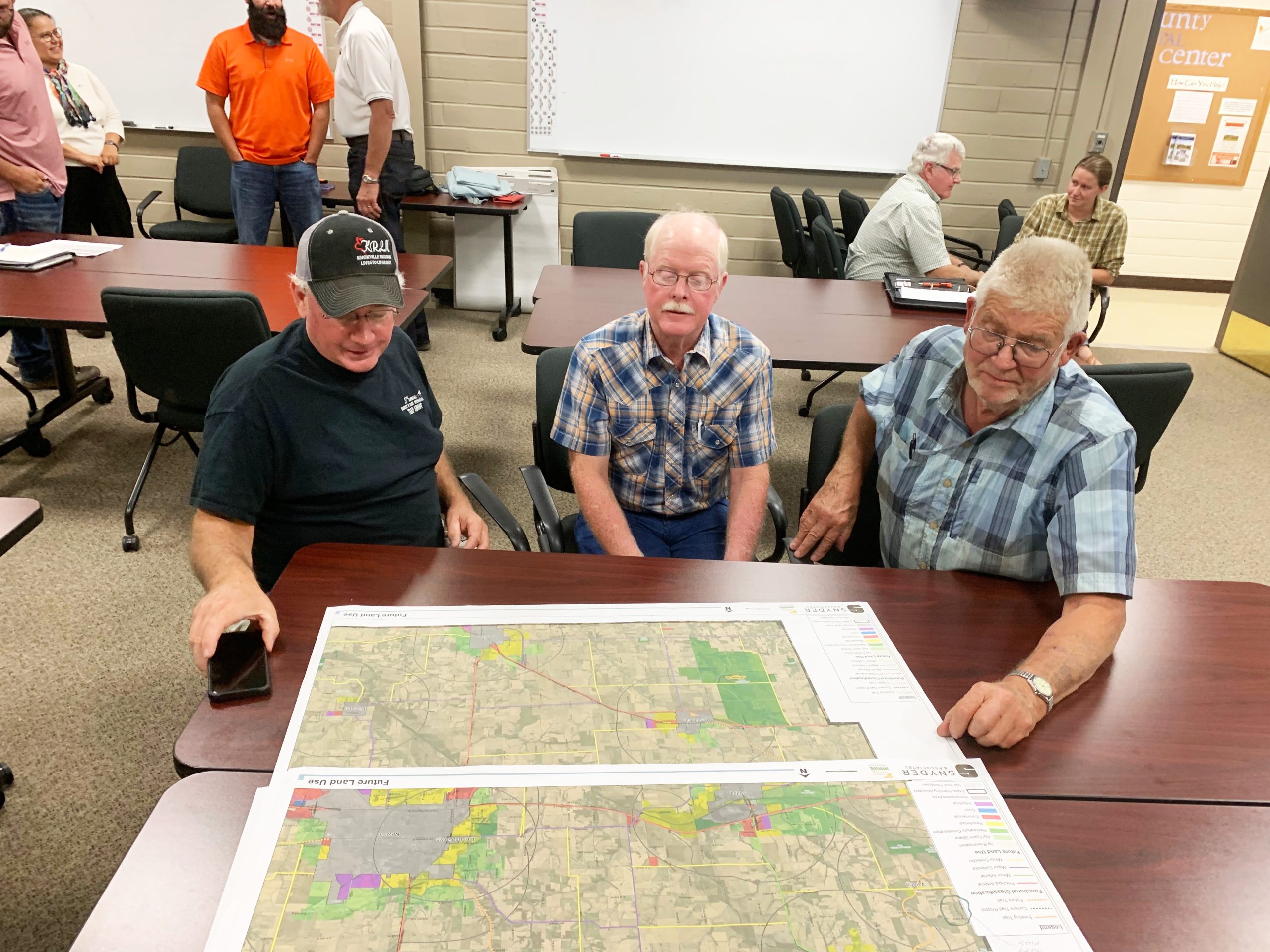 three elderly men look at a map