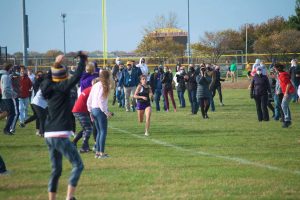 Cross country runner running through line of parents