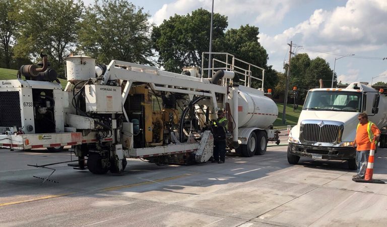 Diamond grinding construction truck.|fault line in a road being measured||large construction truck and workers on a road.|Pavement Technology machine.|Road construction|