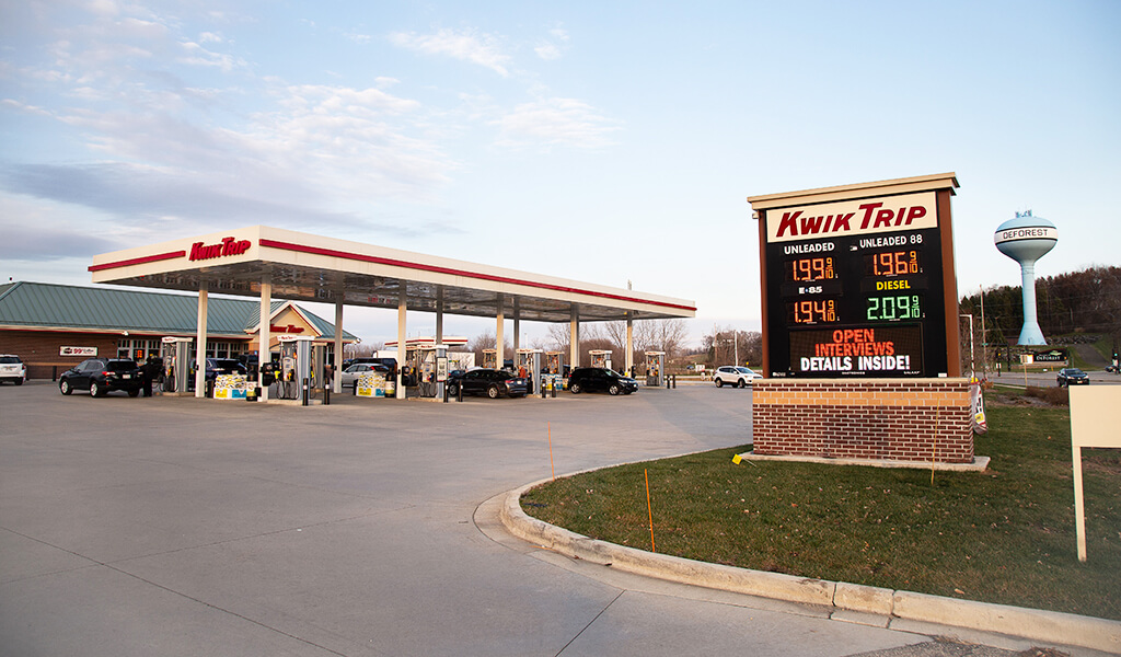 fuel prices are displayed on sign as vehicles enter and exit recently complete kwik trip convenience store|cars entering and exiting recently completed gas station|bio-retention basin enhances stormwater mitigation satisfy local requirements|bio-retention basin enhances stormwater mitigation satisfy local requirements for recently completed kwik trip|vehicle parked next to fuel pump in front of a recently complete kwik trip in deforest wisconsin|vehicles refueling at kwik trip convenience store