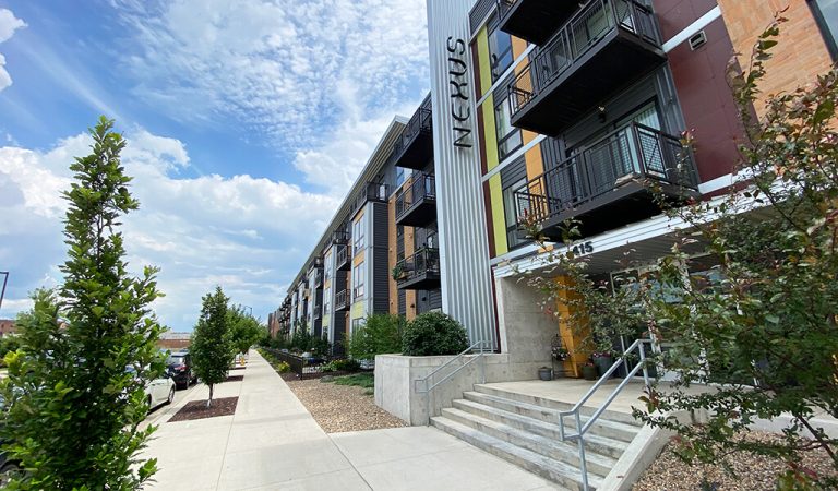 ||||view of the edge entrance from across the street|outside view of holiday inn express and suites|front entrance to the Edge apartments|balconies along the side of the road with parked cars|Holiday Inn express sign|silver rainwater basin