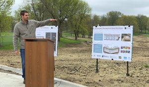 Man stands infront of ourdoor podium presenting a poster