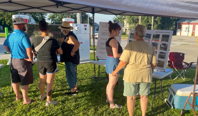 Community members look over public engagement displays at a local event.||Pavilion in Sidney