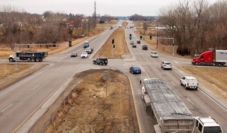 highway with green stoplight and traffic|traffic light control panel filled with wire connections and switches|street image of the traffic light with blue sky