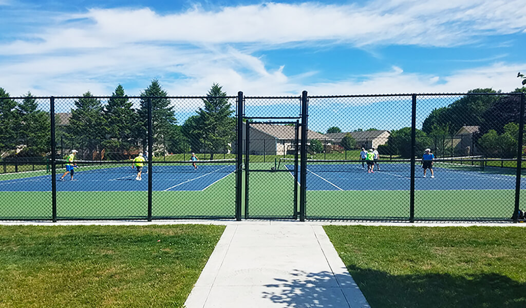 fence entrance to tennis/pickle ball courts||close up view of blue and green tennis courts|Aerial view of eight pickleball courts|||