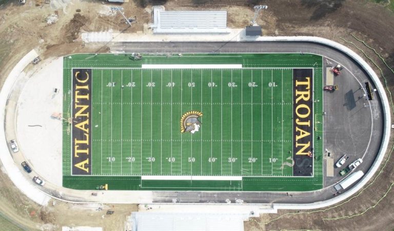 aerial view of Atlantic Trojans football field with surrounding track under construction||aerial rendering of football field/track next to baseball and softball fields.|view looking down on new parking lot filled with cars