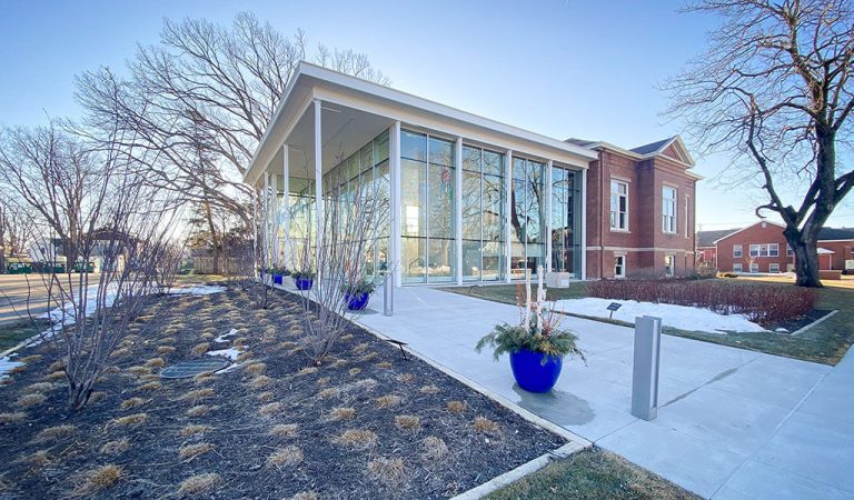 the newly added Lauridsen opera center next to the original Des Moines Opera House|Entryway to new Des Moines Opera House addition|modern glass addition next to antique brick opera house|arching front entrance to antique brick opera house|large brick sign for the Des Moines Opera House|construction crew updating the exterior of des moines opera house|glass doors to the Lauridsen Opera Center