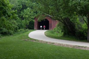 A couple walking onto a covered bridge on the Easter Lake Trail in Polk County.