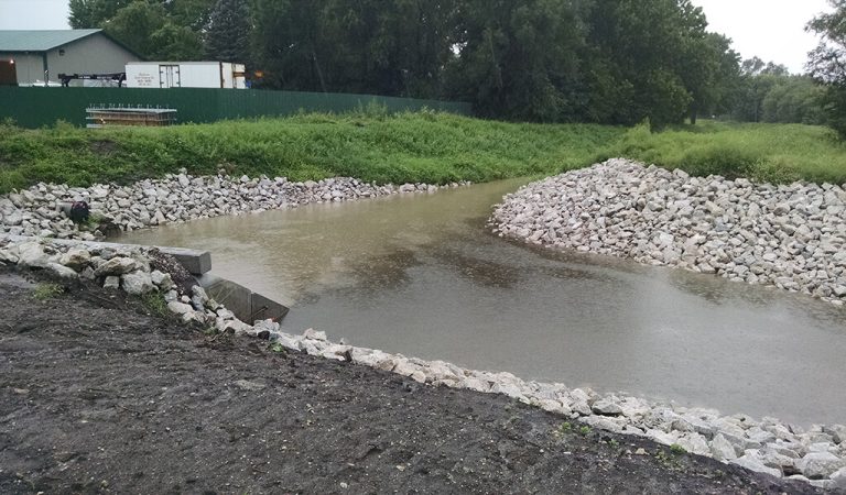 curved stormwater basin with new rock lining the shores||bar graph showing flooding occurrences in a 10 year span|a stream of stormwater flooding running through a residential yard|Hamilton drain basin filled and surrounded by native plants|||a strip of stormwater infrastructure parallel to the road|a new box culvert with riprap rock along the edges