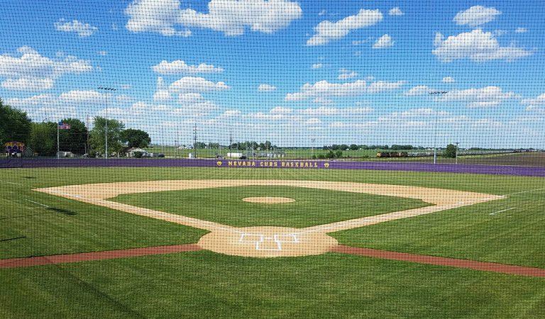 baseballfield through netting on a blue sky day|construction machinery flattening area for baseball field|red tractor pulls yellow container dropping sand|fans in the stands at a baseball game|Large baseball sign on the back of bleachers|aerial view of dirt baseball diamond under construction