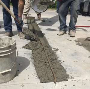 two men shovel wet concrete into place