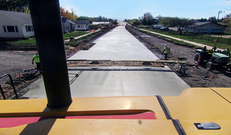 newly poured concrete roadway|construction workers pouring concrete for stormwater drainage|Cement truck pours wet concrete onto newly established roadway|construction workers in large hole for sanitary sewer|crews lay wet cement