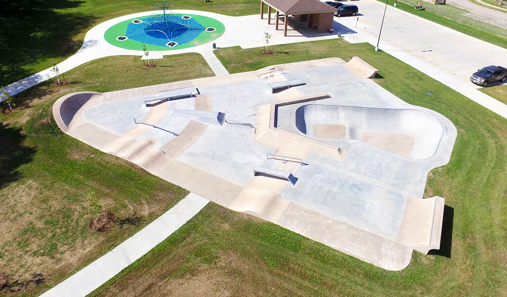 aerial photo of skate park and climbing structure|blue and green climbing structure
