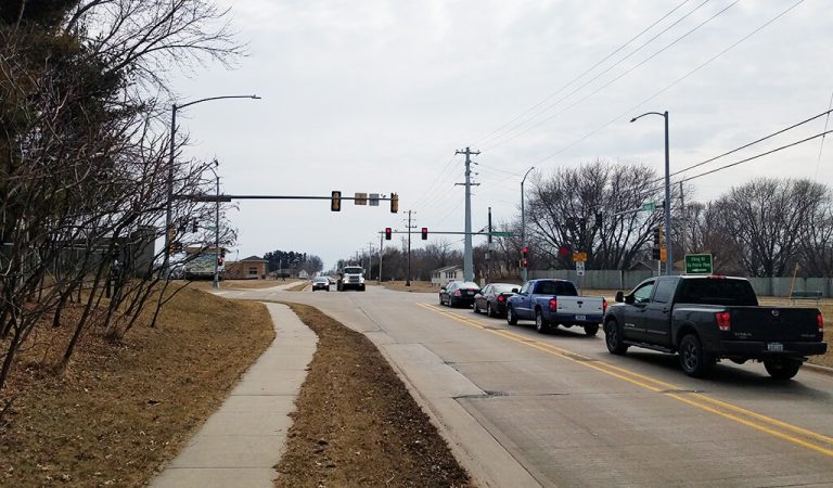 Vehicles waiting at a traffic-light controlled intersection.|Sign marking the entrance to The Villages at Pinnacle Prairie next to Greenhill Road street sign.|Vehicles navigating through a busy traffic-light controlled intersection.|Vehicles navigating through a busy signalized intersection.|||||community members viewing proposed plans|cars moving through a busy intersection|Large stone neighborhood sign