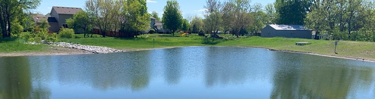 recent rehabilitated wildflower pond improving stormwater retention|Satellite image of pond surrounded by residential neighborhoods|Satellite image of pond surrounded by farmland|large cement connector sits on grass before being placed|Drone aerial photos create 3D visual of pond area|Aerial view of pond in the midst of residential housing|Aerial view of pond in the midst of residential housing|Pond surrounded by dirt in the midst of construction|Pond water that is shallow and scummy|Satellite image of pond surrounded by residential neighborhoods|Aerial view of pond in the midst of residential housing|Drone aerial photos create 3D visual of pond restoration area||